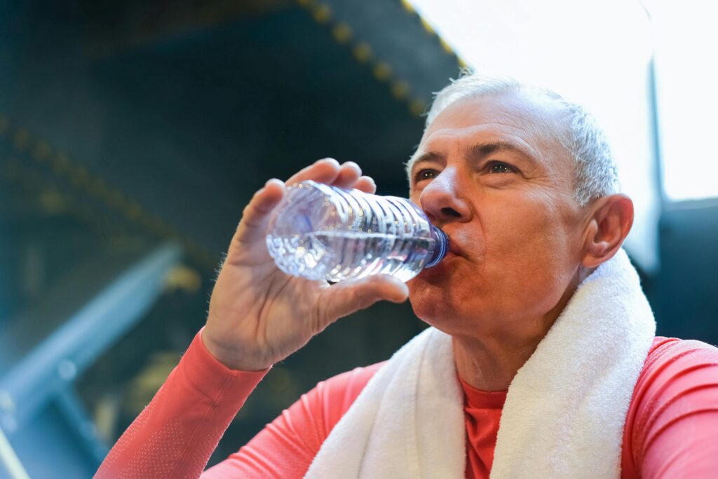 senior man drinking water after workout