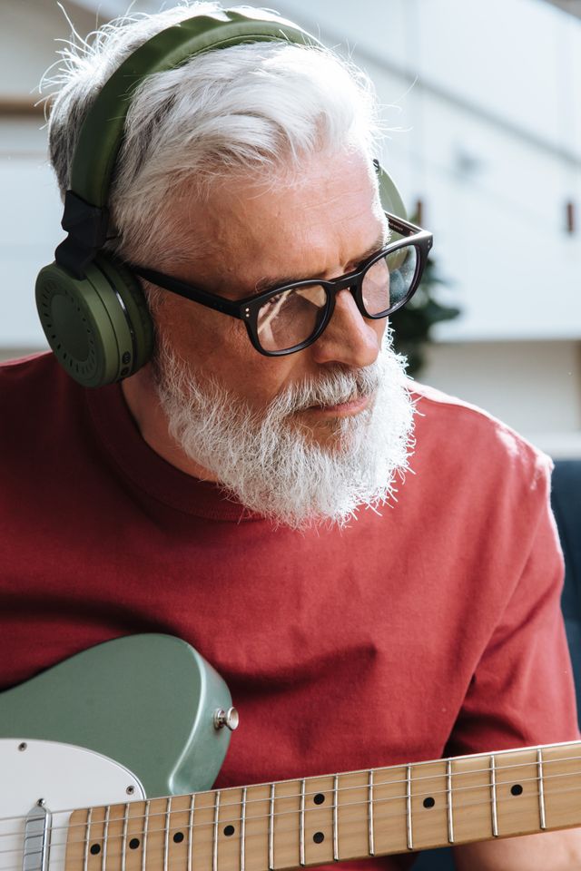 senior man with headphones playing guitar